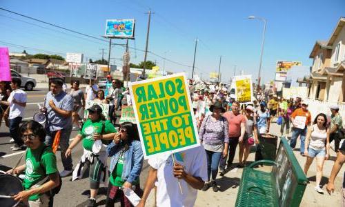 A group of 人 marching with a sign that reads "Solar power to the 人."